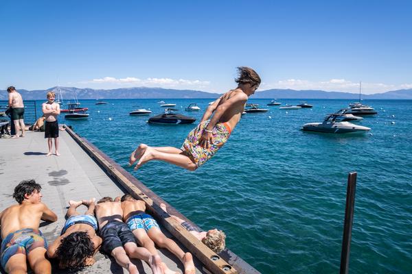 Person jumping over 4 people into water off a dock