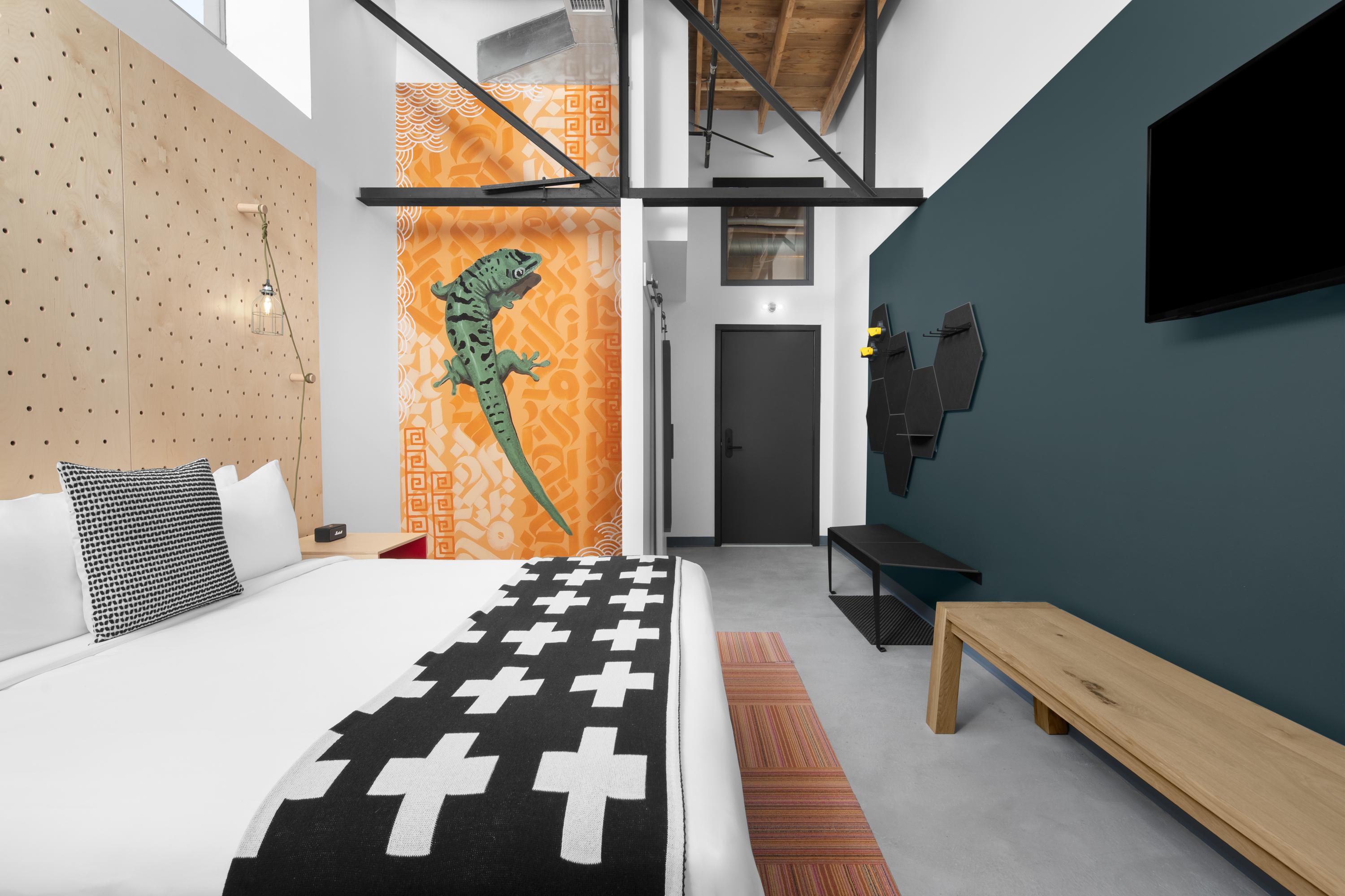 High-ceilinged room with king bed and funky lizard art